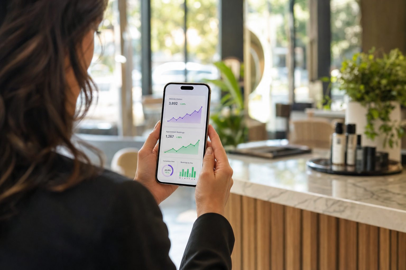 A business owner reviewing website analytics and appointment bookings on her phone